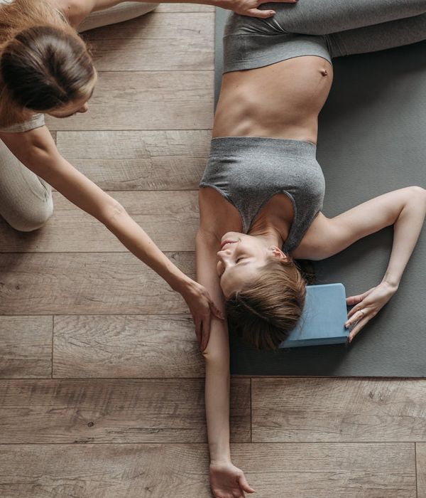 Pregnant woman gently stretching on a yoga mat.